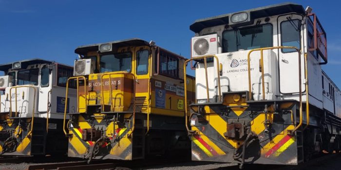 Two Trains Parked Side By Side Under A Clear Blue Sky.